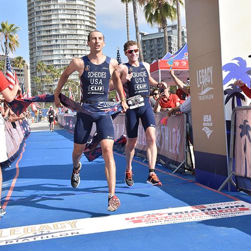 Aaron Scheidies crossing para triathlon finish line with his guide.