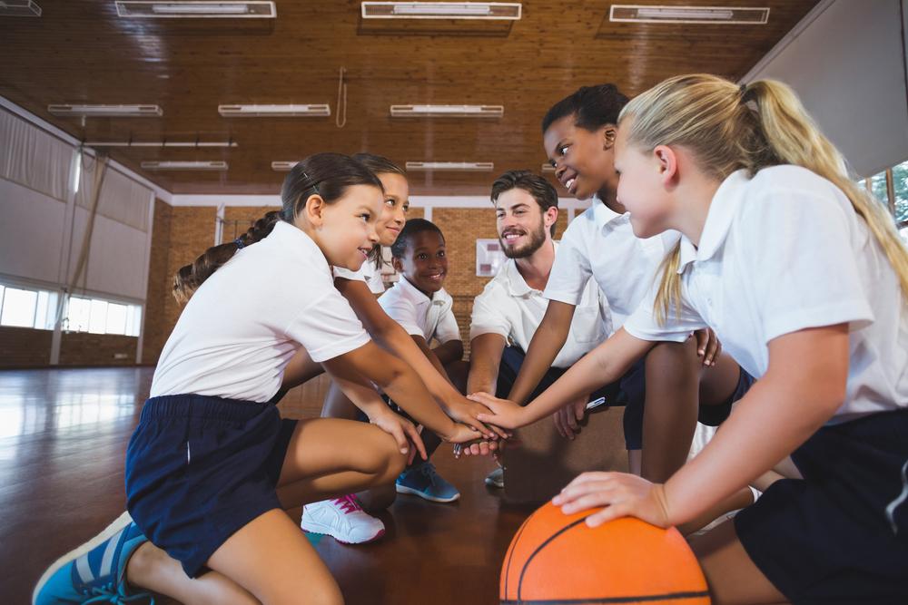 Young girl's basketball team in a huddle with coach.