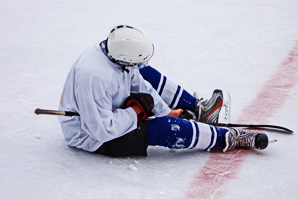 Hockey player sitting on ice alone.