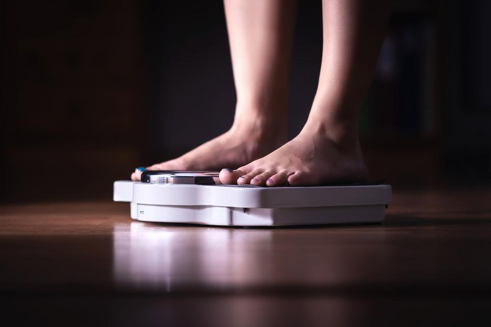 Close up of feet on scale in dark room.