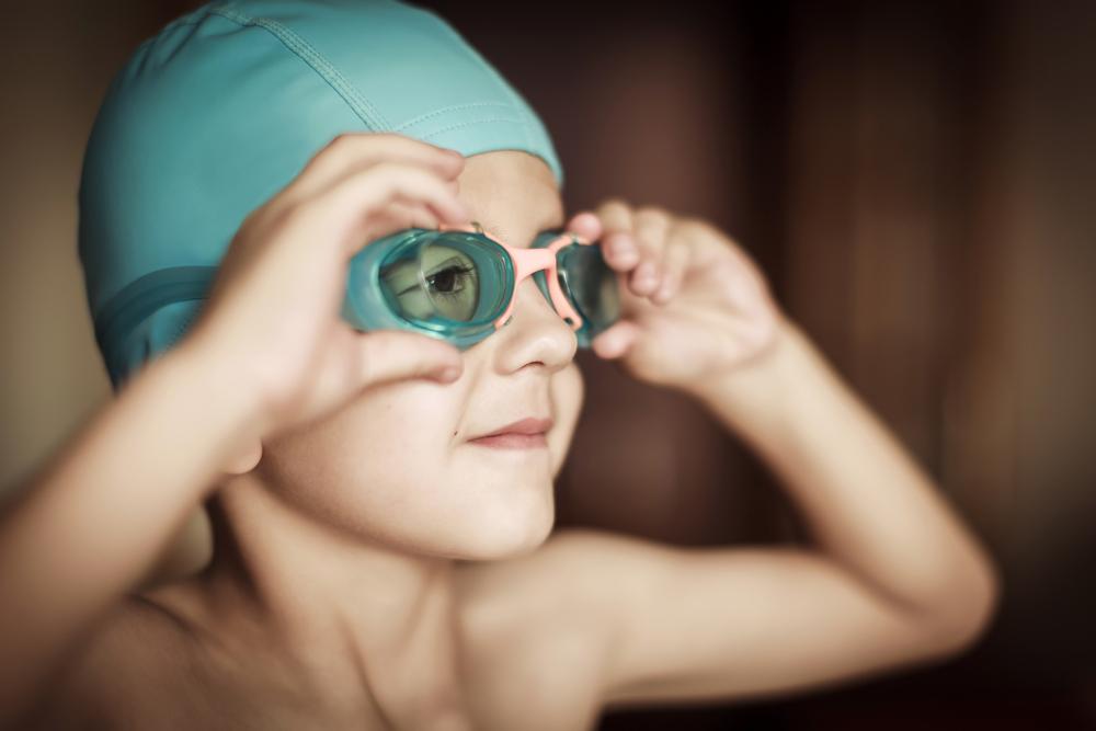 Close up of young boy wearing swim cap and goggles.