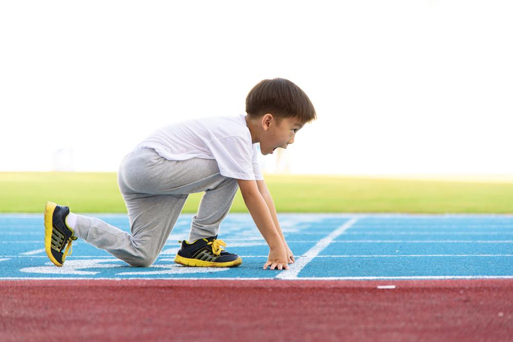 Young asian boy on a track about to run.