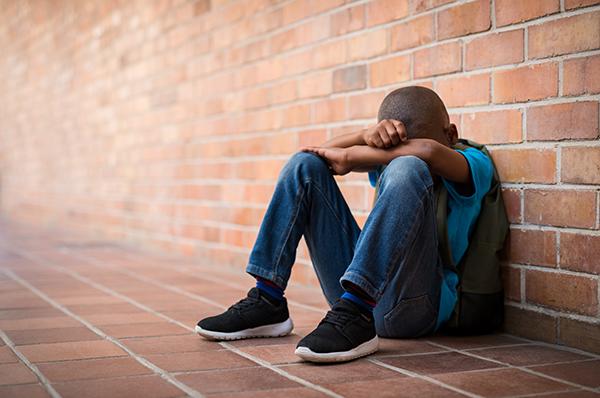 Black boy sitting alone and upset.