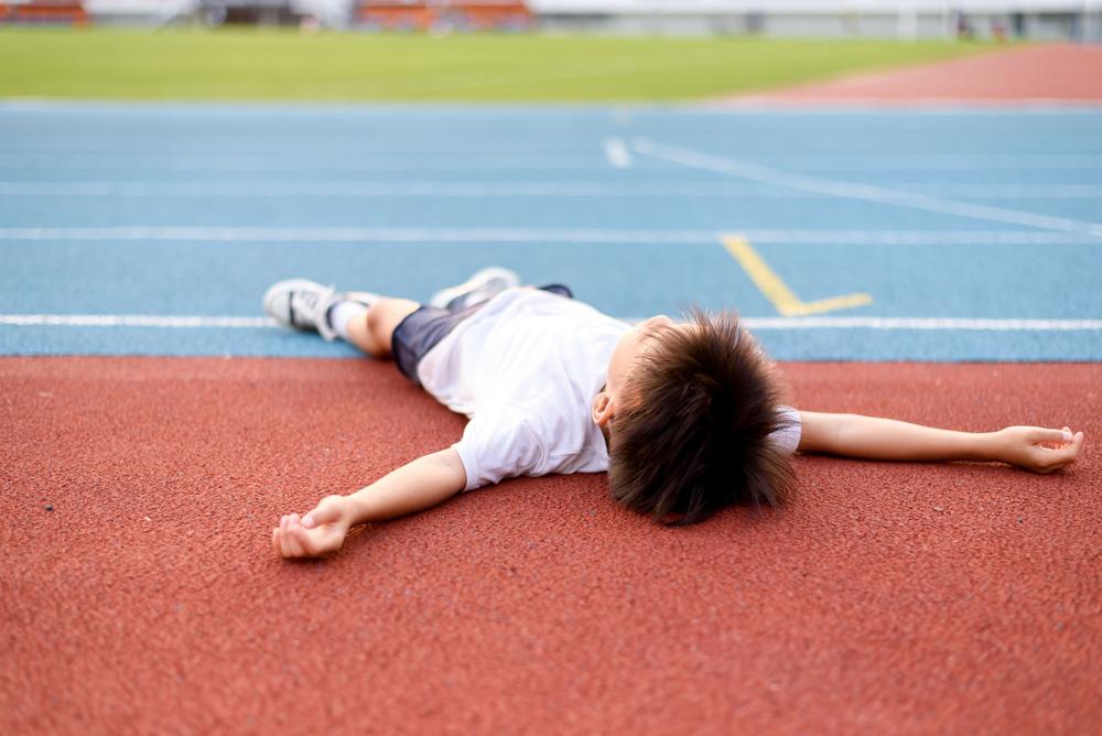 Kid laying down on track, tired.