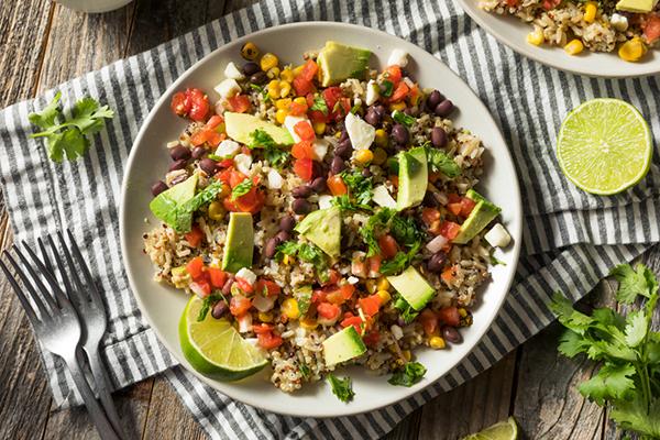 A burrito bowl with rice, beans, and vegetables.