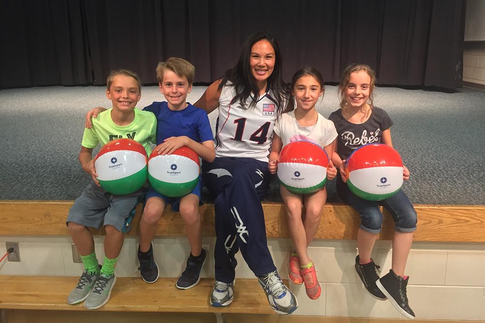 Candace Vering sitting with kids holding TrueSport branded beach balls.