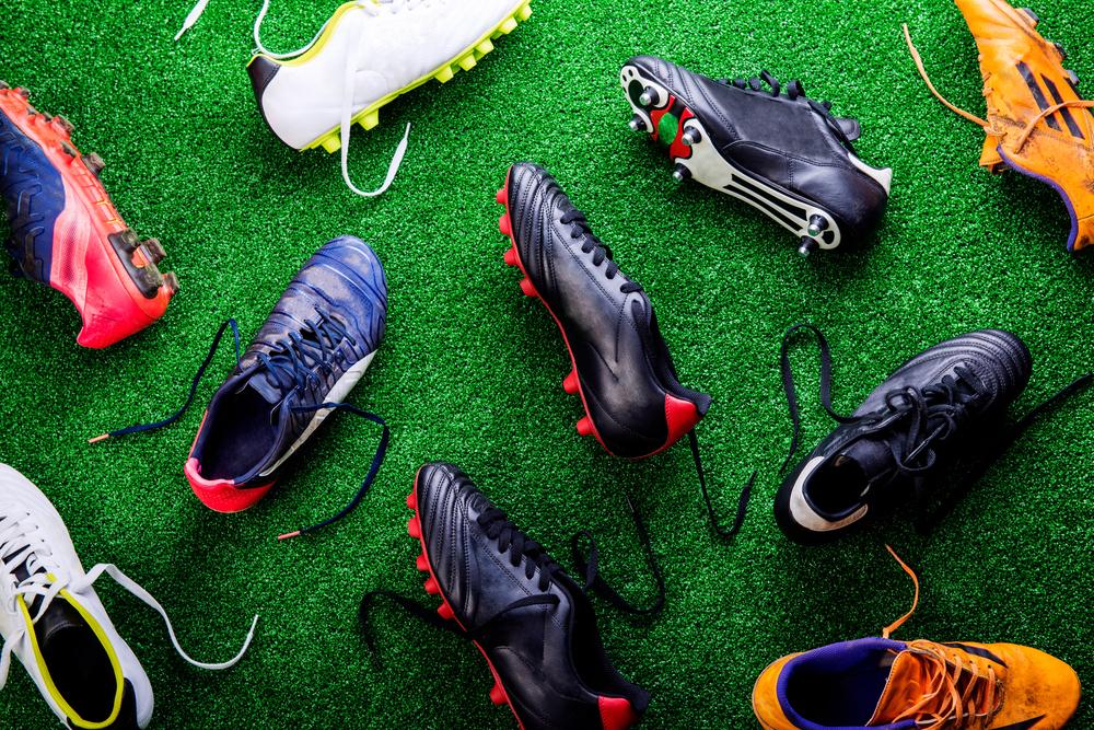 A variety of sport shoes on grass.