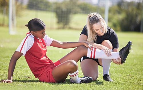 Trainer looking at athlete's ankle.