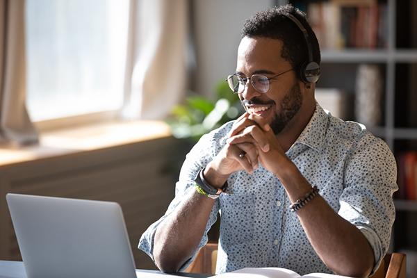 Young male coach in front of computer smiling.