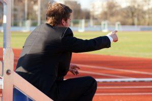 Male coach on side of track pointing.