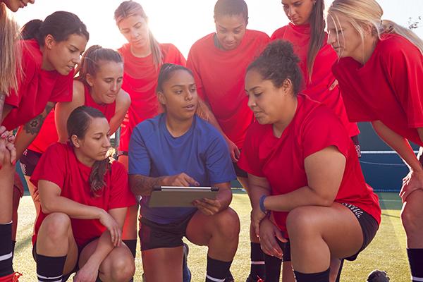 Coach talking to teen girl soccer team.