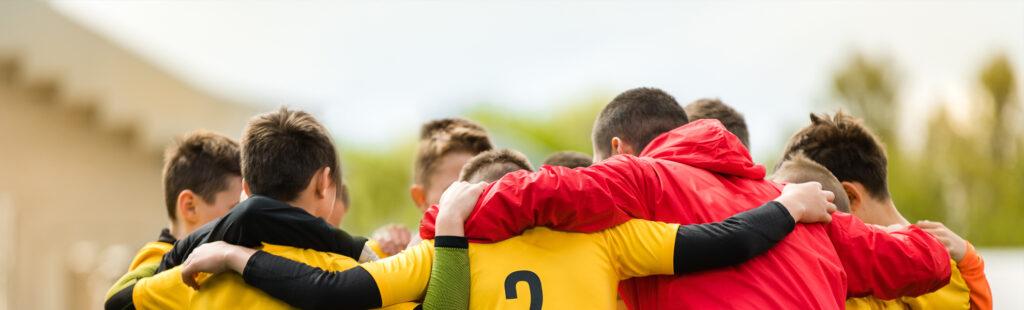 A coach in a huddle with his youth teen male team.