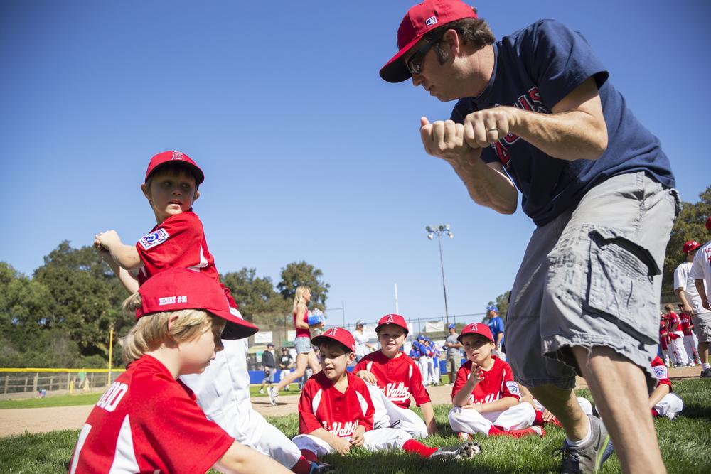 Male baseball coach working with young team.