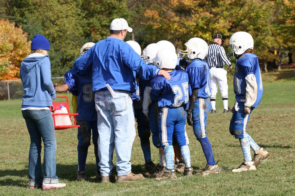 Coach in a huddle with young football players.