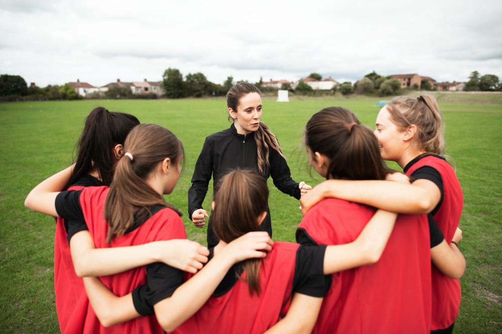 Female coach talking to young female soccer team.