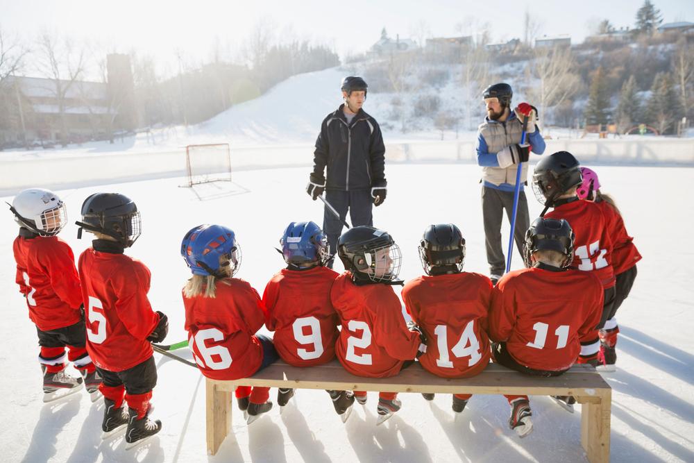 Hockey coaches talking to young team on ice.