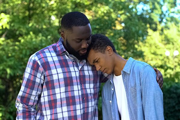 Father comforting teen son.