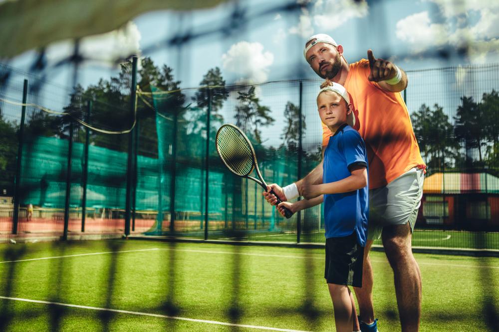 Coach helping young athlete train for tennis.