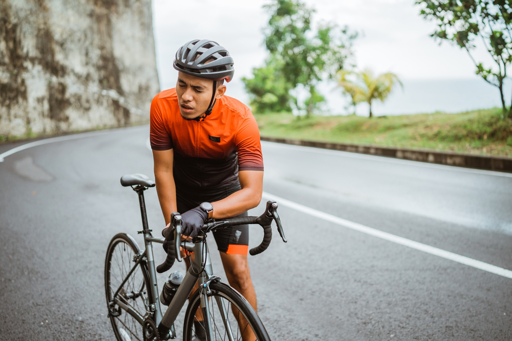 Tired cyclist standing next to bike.