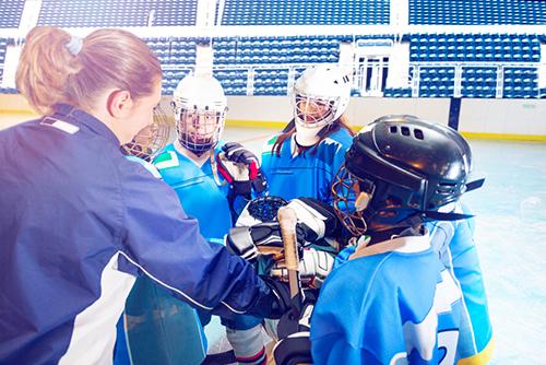 Female hockey coach talking to young team.