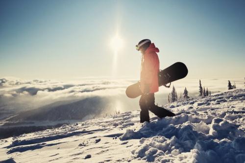 Female snowboarder walking on mountain.