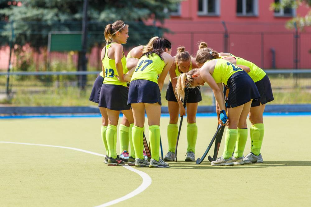 Teen girls huddling during a field hockey game.