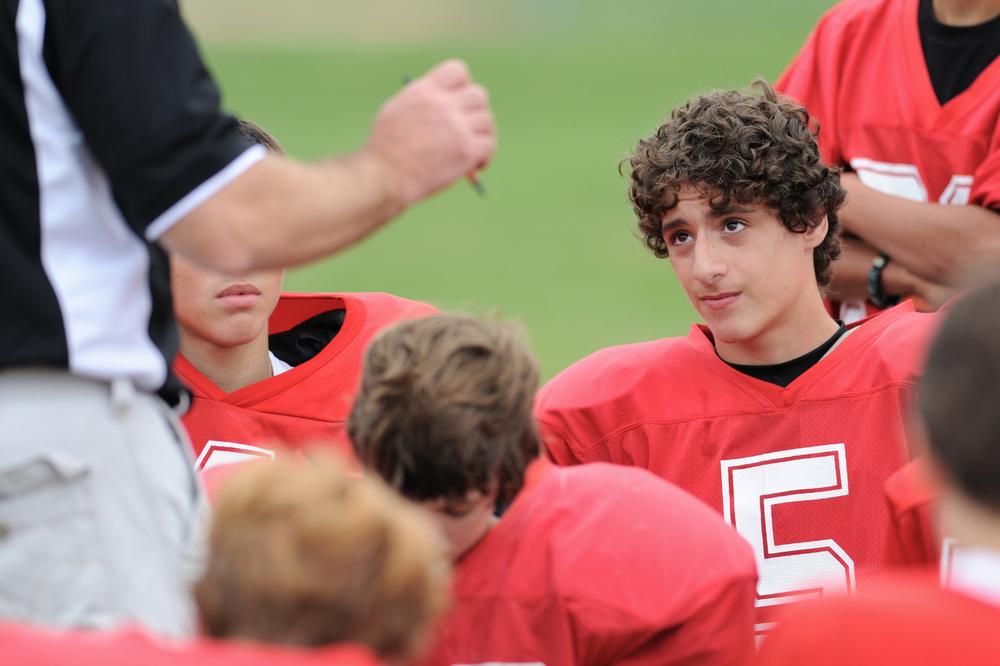 Teen male football player looking at coach.