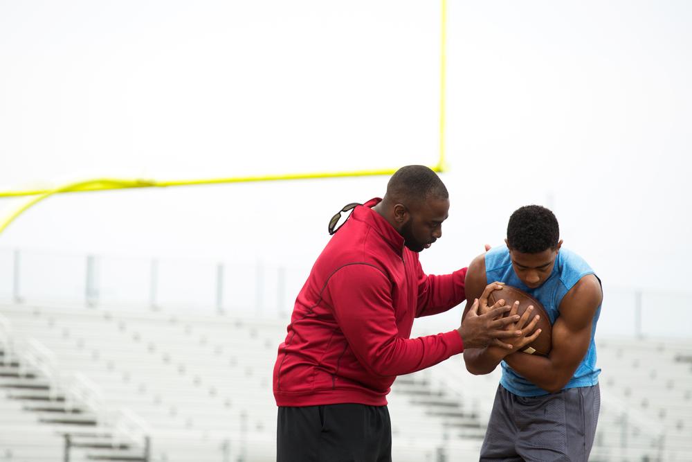 Young football player with coach or father.