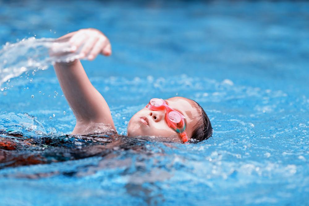 Young girl swimming with goggles on.