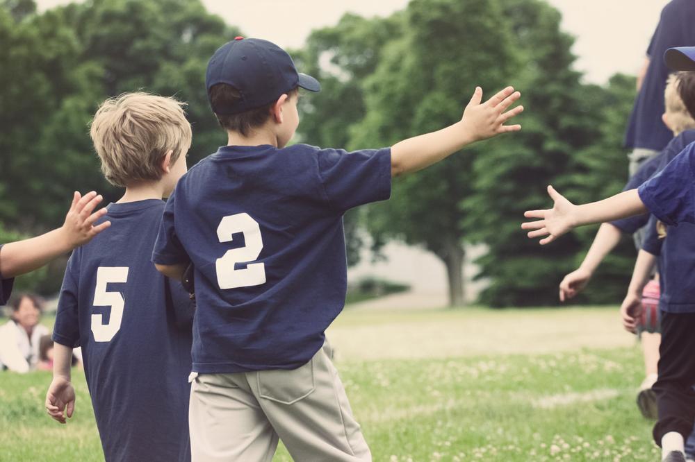 Young baseball players high fiving after game.