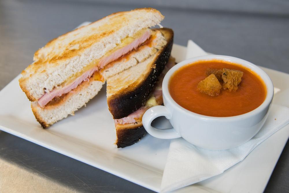 Grilled ham and cheese sandwich with a cup of tomato soup.