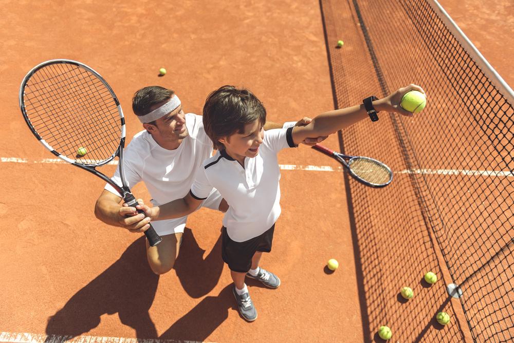 Young boy being coached on tennis.