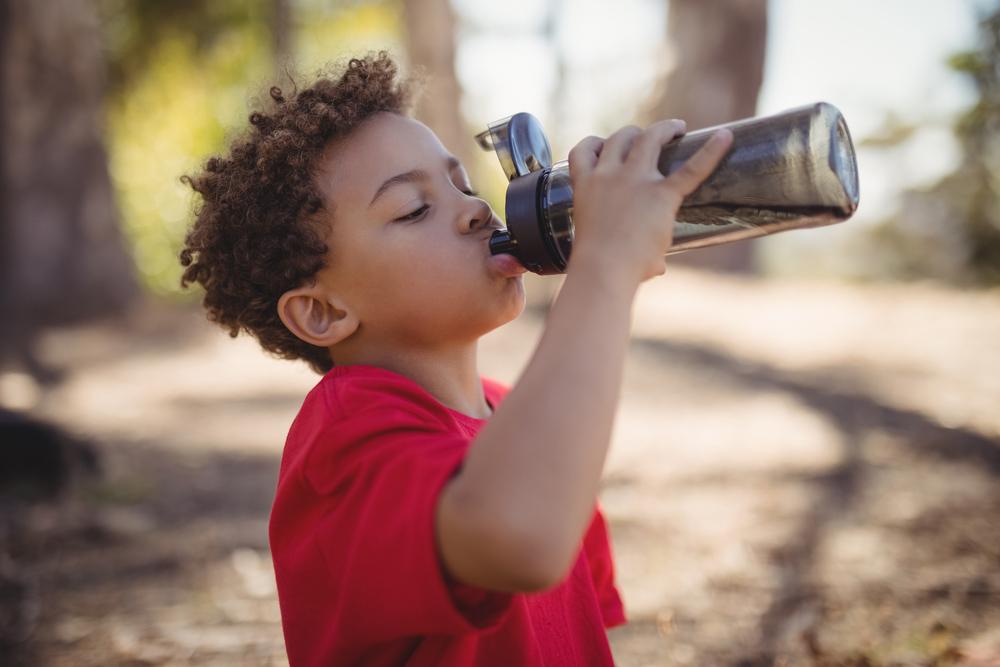 Young boy drining from reusable water bottle.