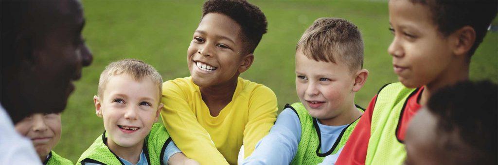 Diverse group of young boys smiling at their sport coach.