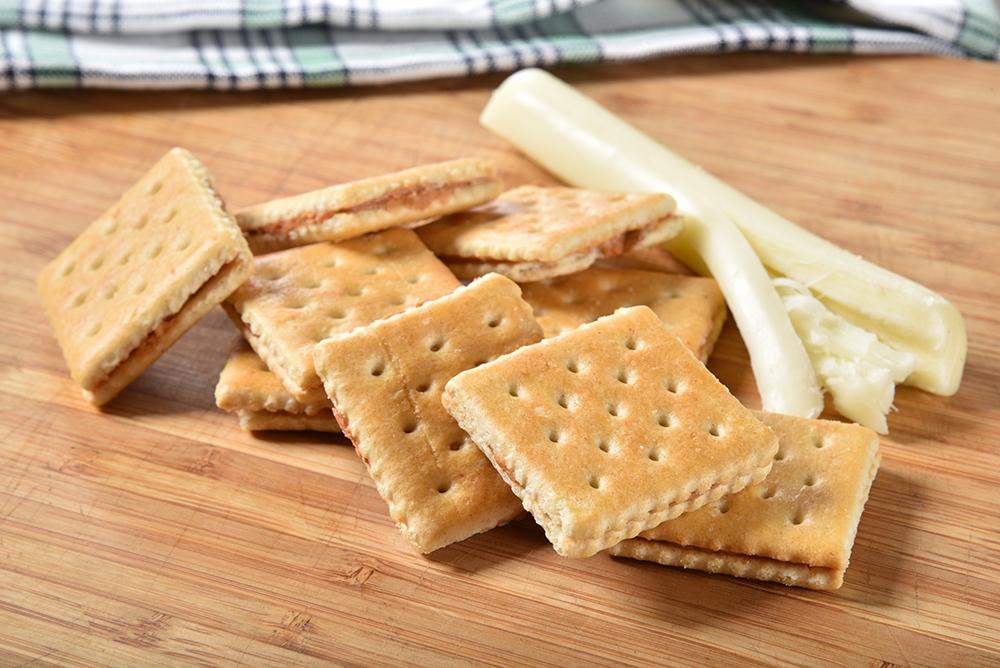 Cracker sandwiches and string cheese on a table.