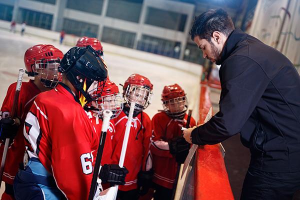 Hockey coach talking to young team members.