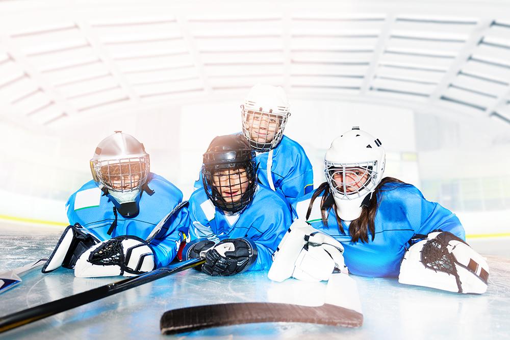 Young hockey players laying on ice together.