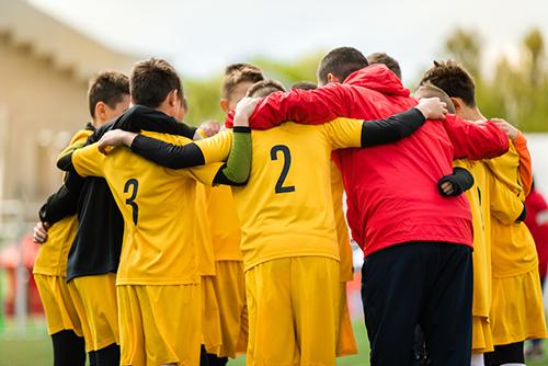 Teen boy sports team in a huddle.