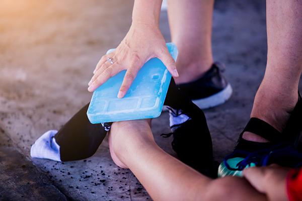 Adult holding an ice pack against a child's ankle.