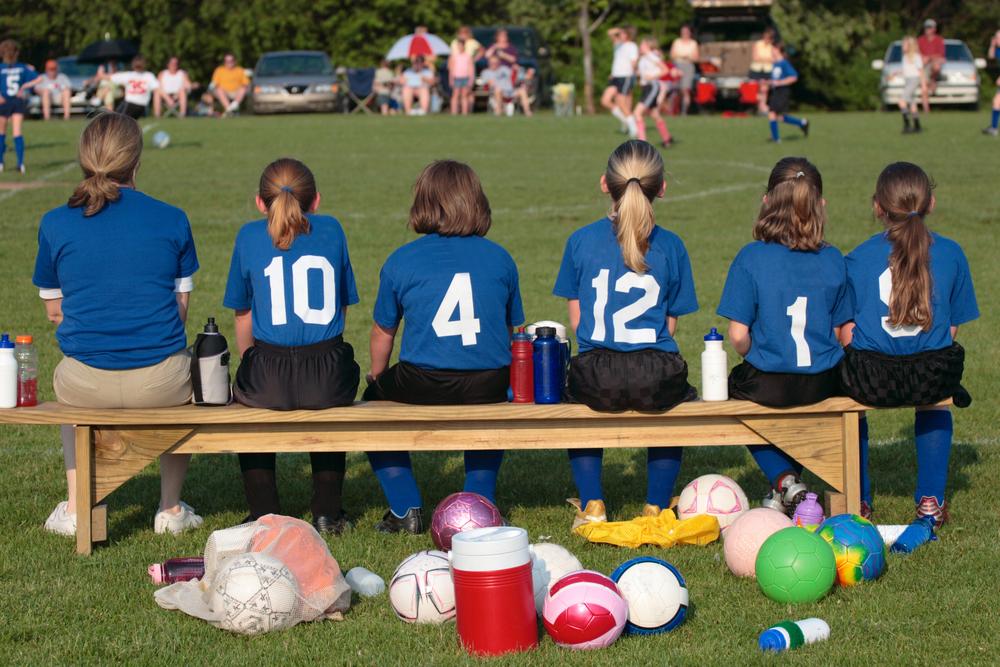 Girls soccer team from behind on bench.