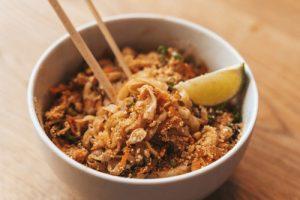 Paid thai in a bowl with chopsticks.