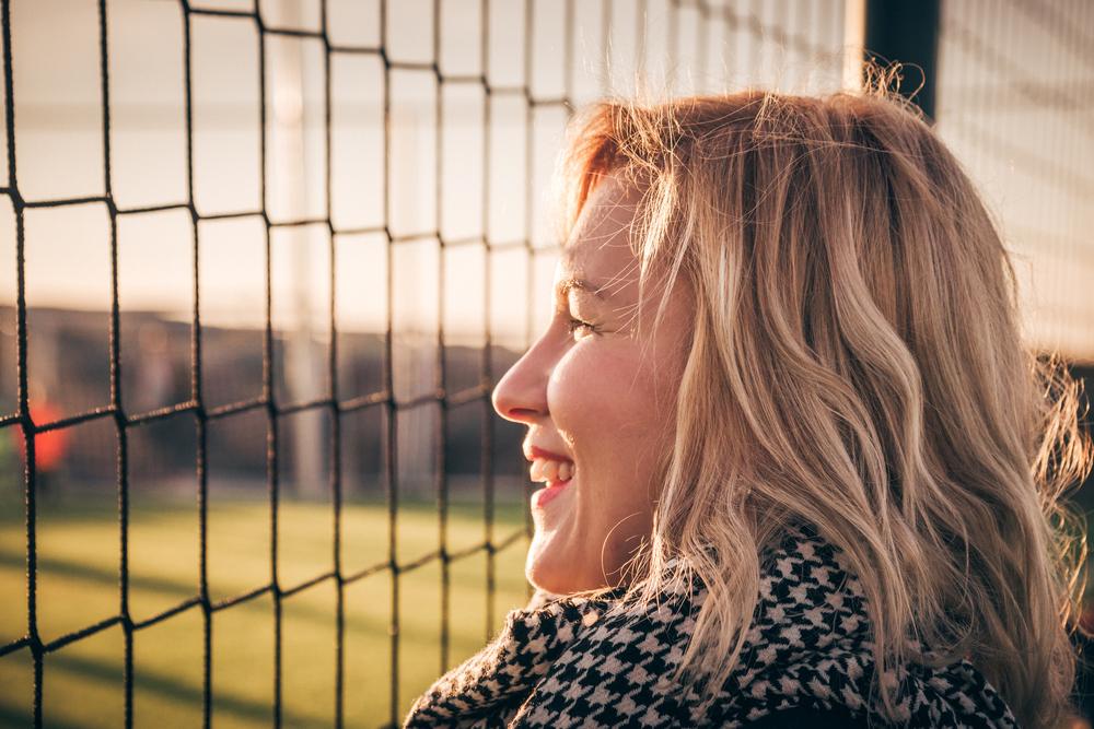 Close up of white mom smiling at fence.