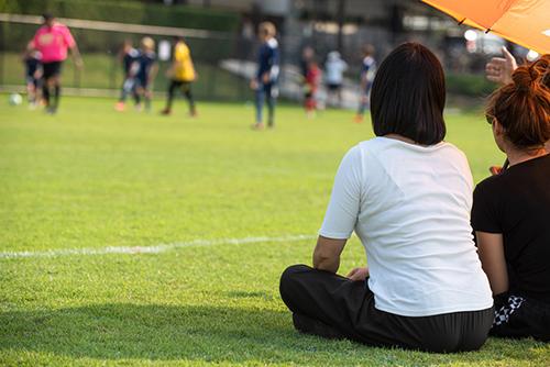 Parents sitting on sideline of soccer game.