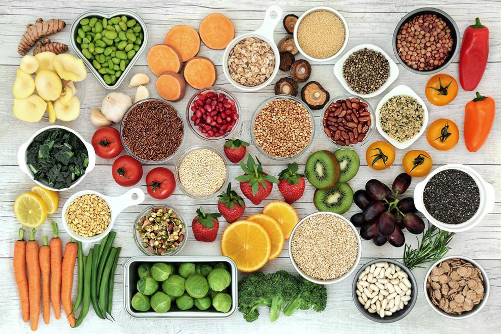 Variety of fruits, vegetables, grains, and nuts on a wood table.