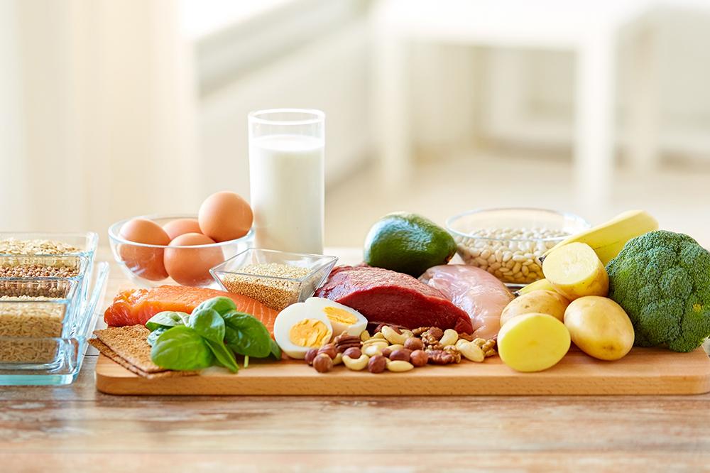 Table full of foods that provide protein, including eggs, meat, and vegetables.