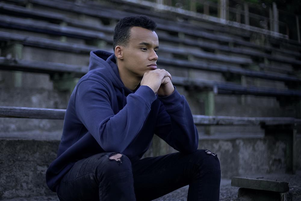 Teen boy sitting on bleachers thinking pensively.