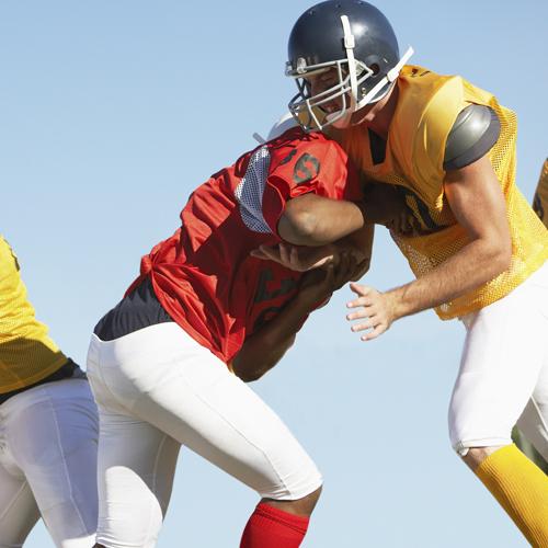 two male american football players tackling each other