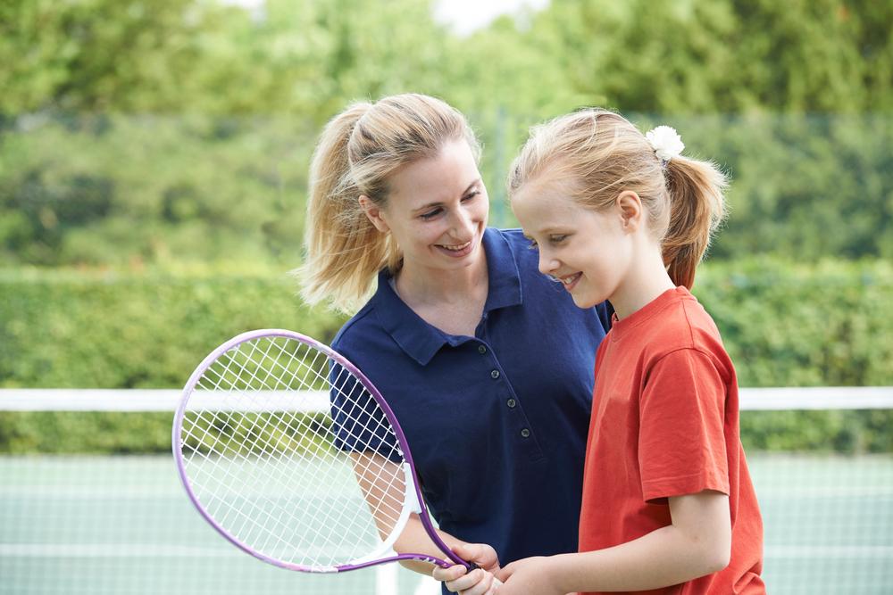 Woman coach talking to young female tennis athlete.