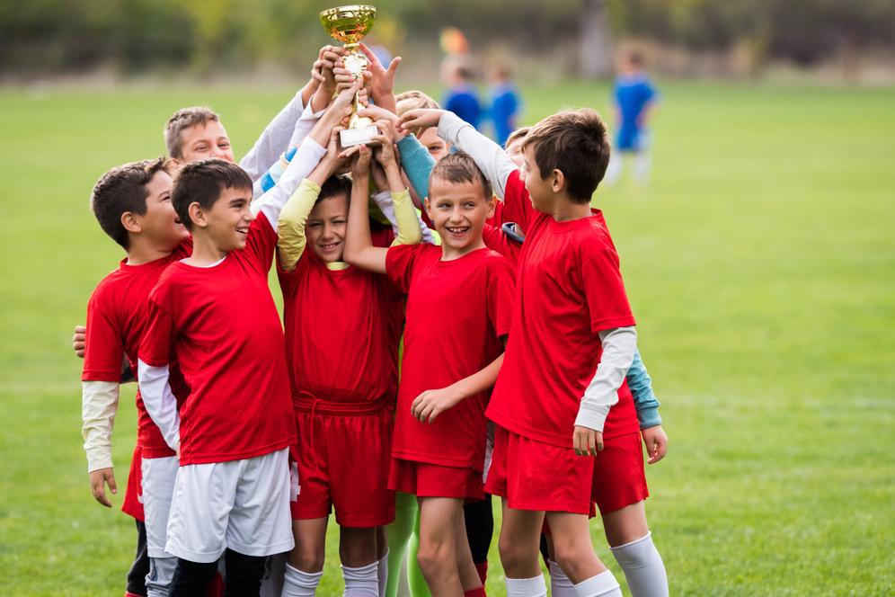 Young male soccer team holding a trophy together.