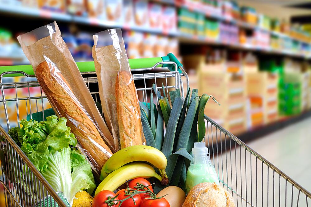 Shopping cart full of bread, fruits and vegetables.